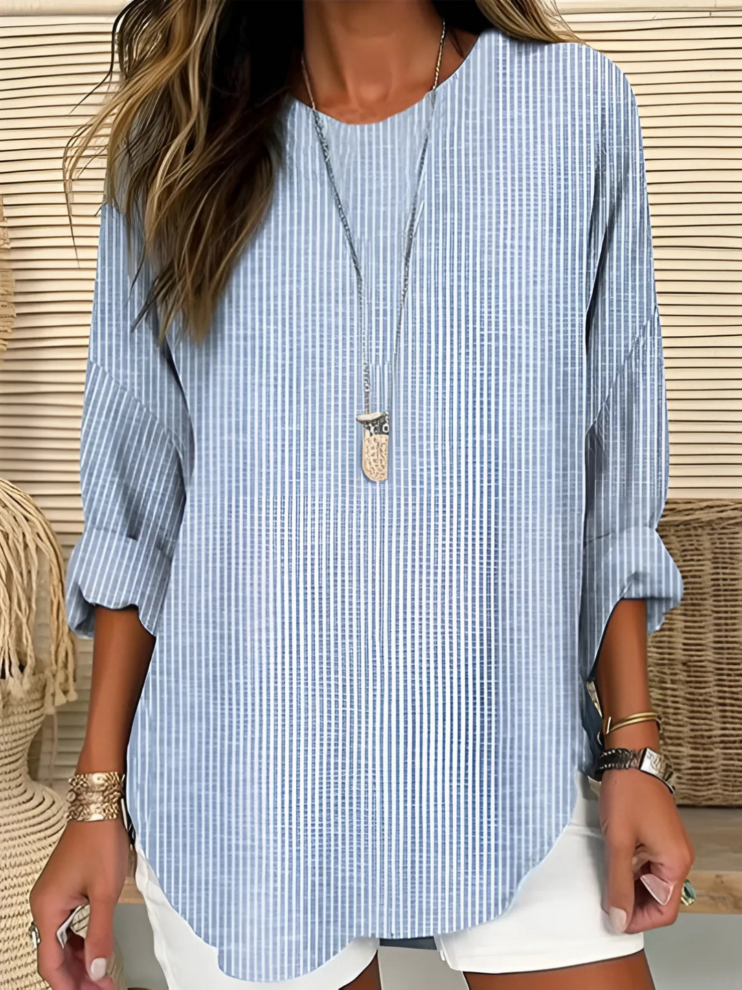 Woman wearing a light striped blouse as an easy summer layer over a breezy warm weather outfit